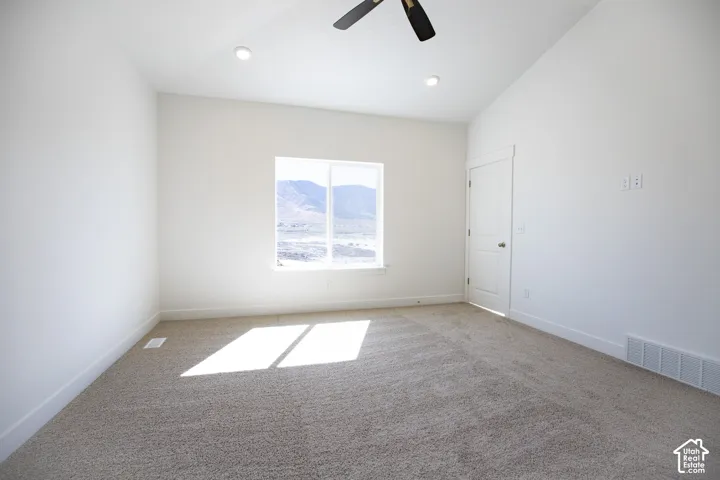 Primary bedroom with vaulted ceiling and ceiling fan.