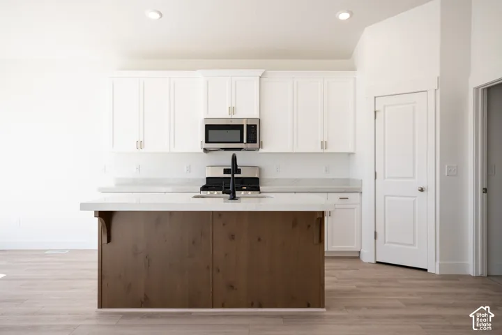 Terrific kitchen with 42" uppers, painted white wood cabinets, stained wood island, quartz slab countertops, gas range, microwave, dishwasher and disposal.