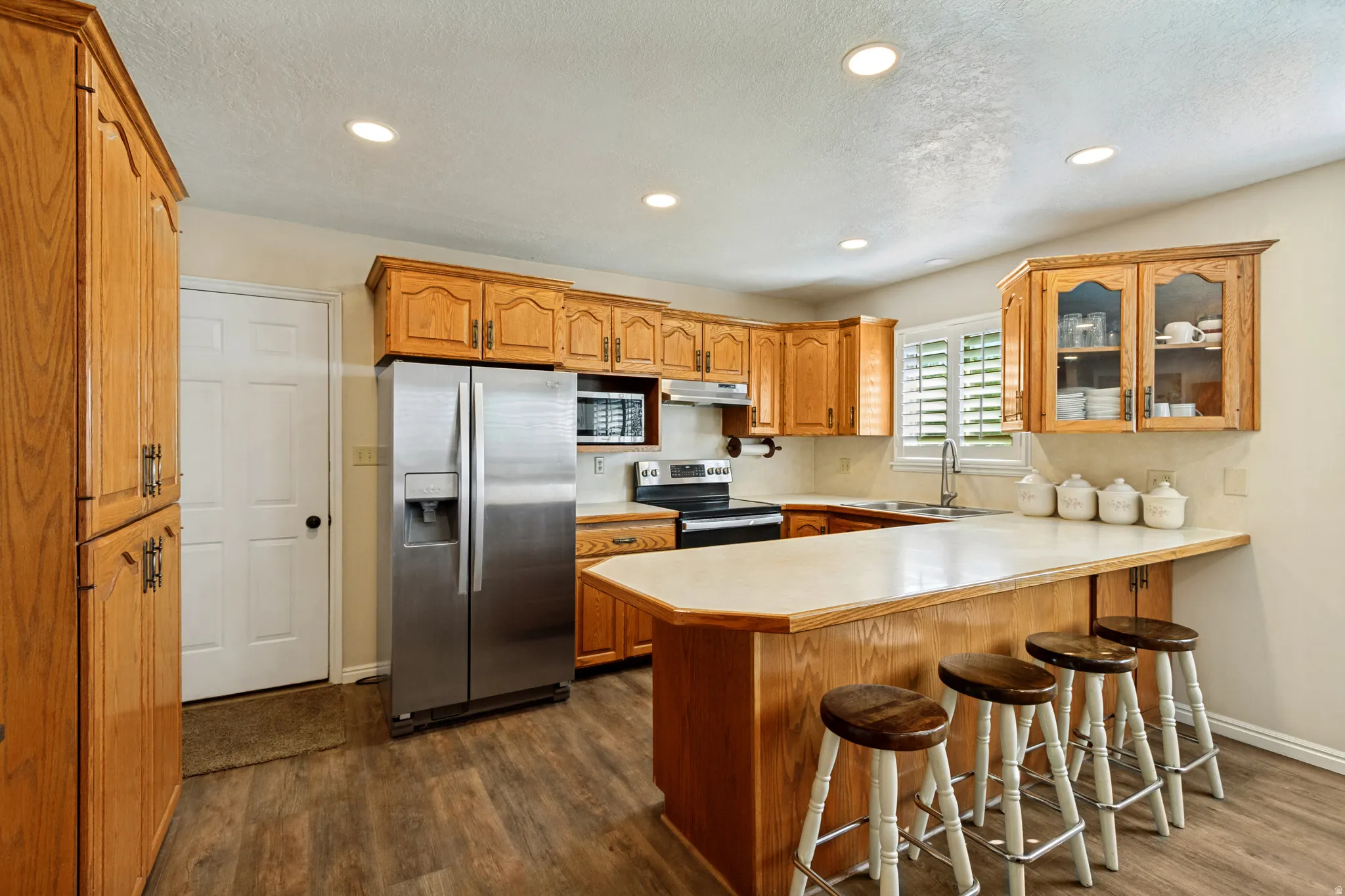 Kitchen featuring wood-finish cabinetry, stainless steel appliances, a breakfast bar, and recessed lighting