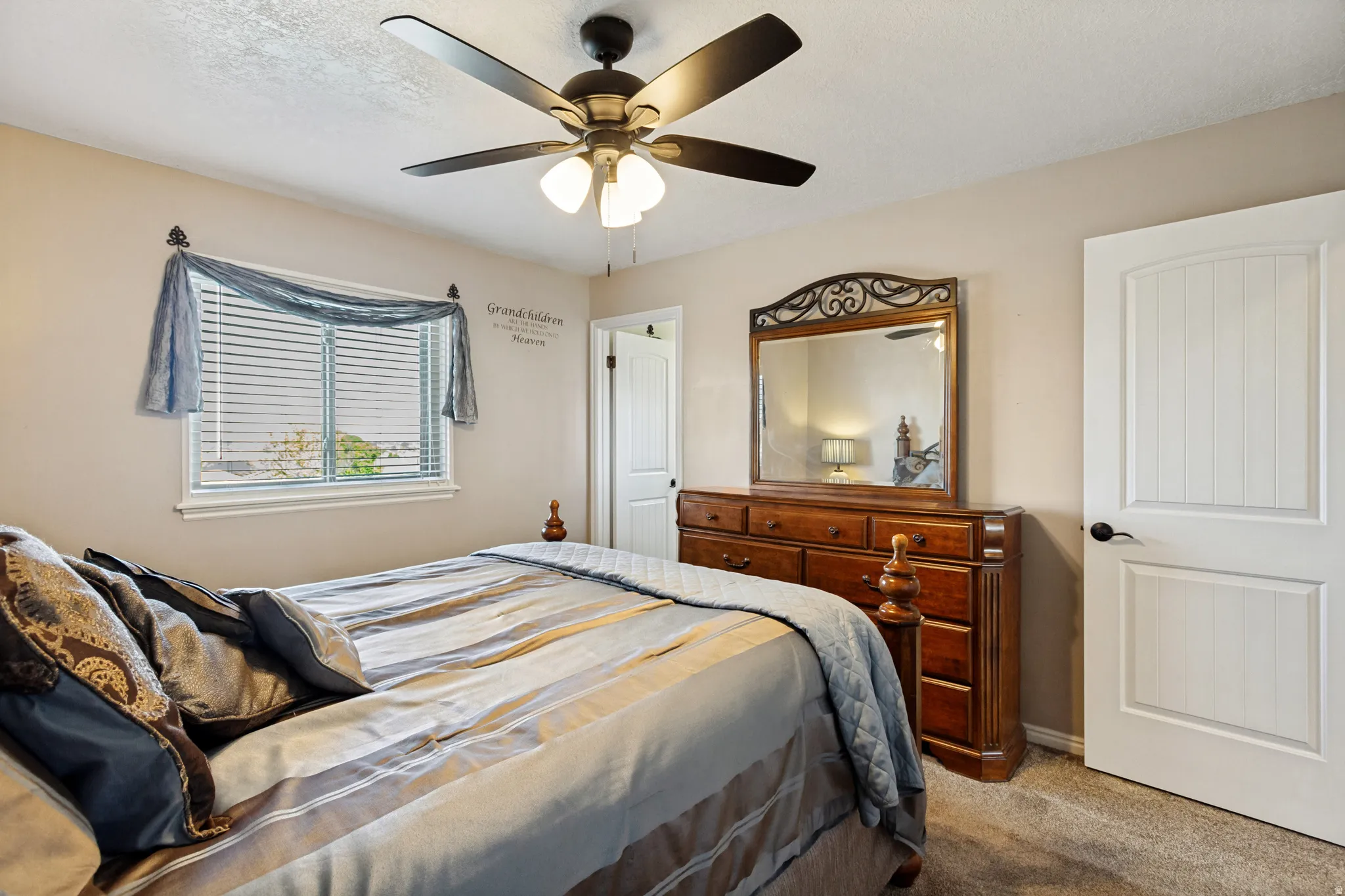 Ceiling fan with integrated lighting, window with blinds, paneled interior door with dark hardware, carpeting, and light neutral wall paint