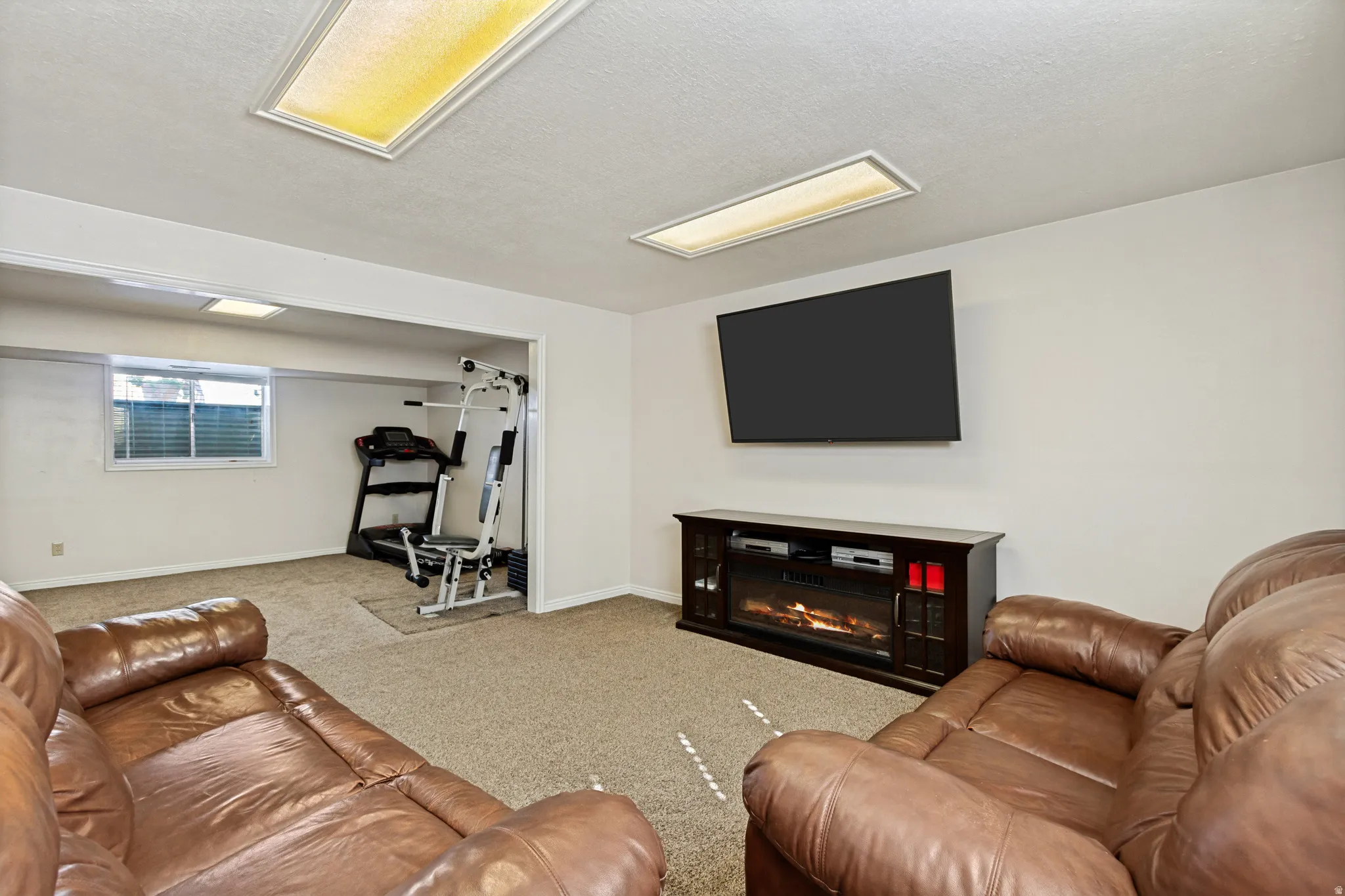 Recessed lighting, wall-mounted television, and a built-in media console with an electric fireplace