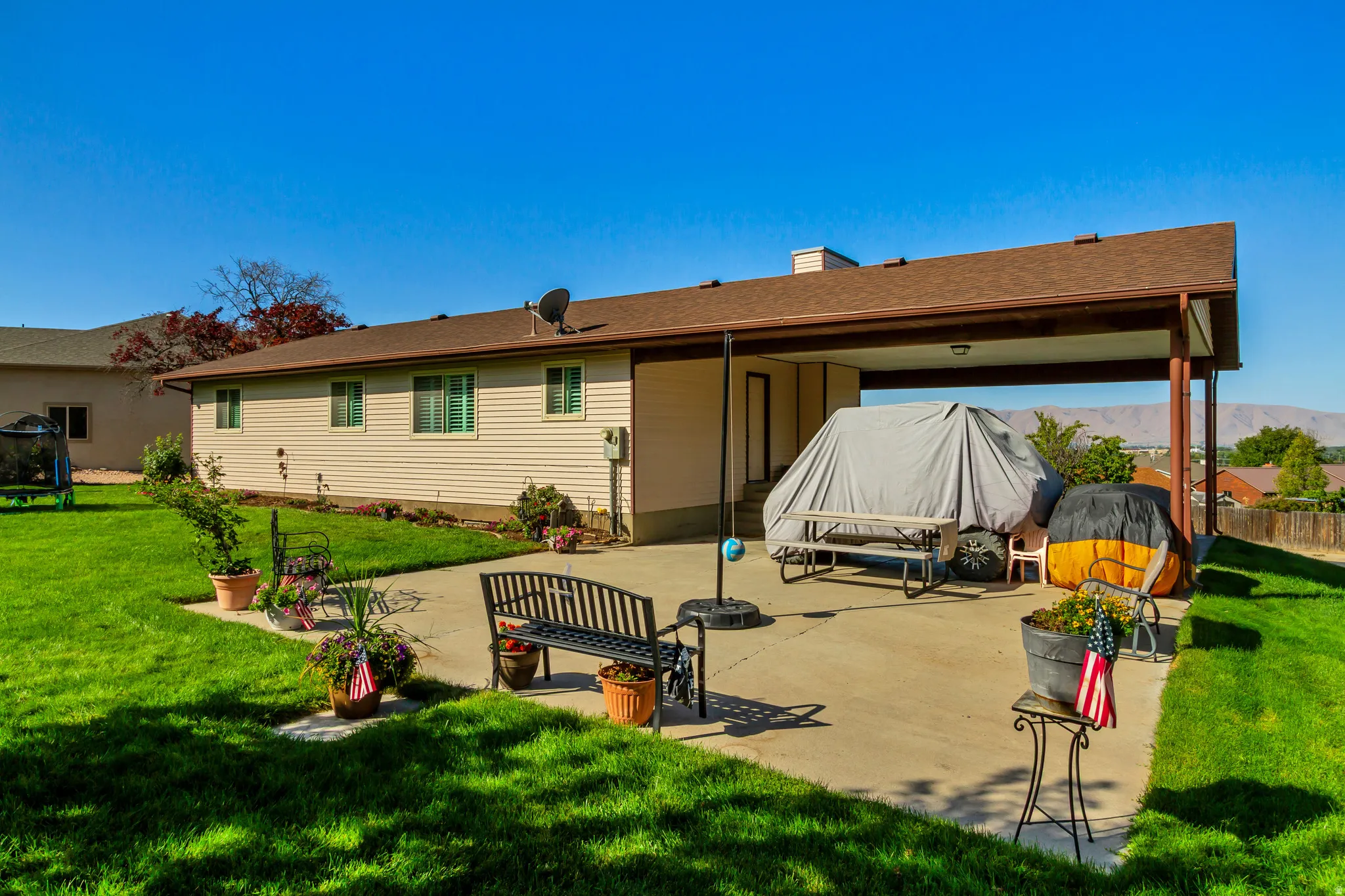 Expansive backyard with a covered patio, concrete surfacing, and a large lawn area