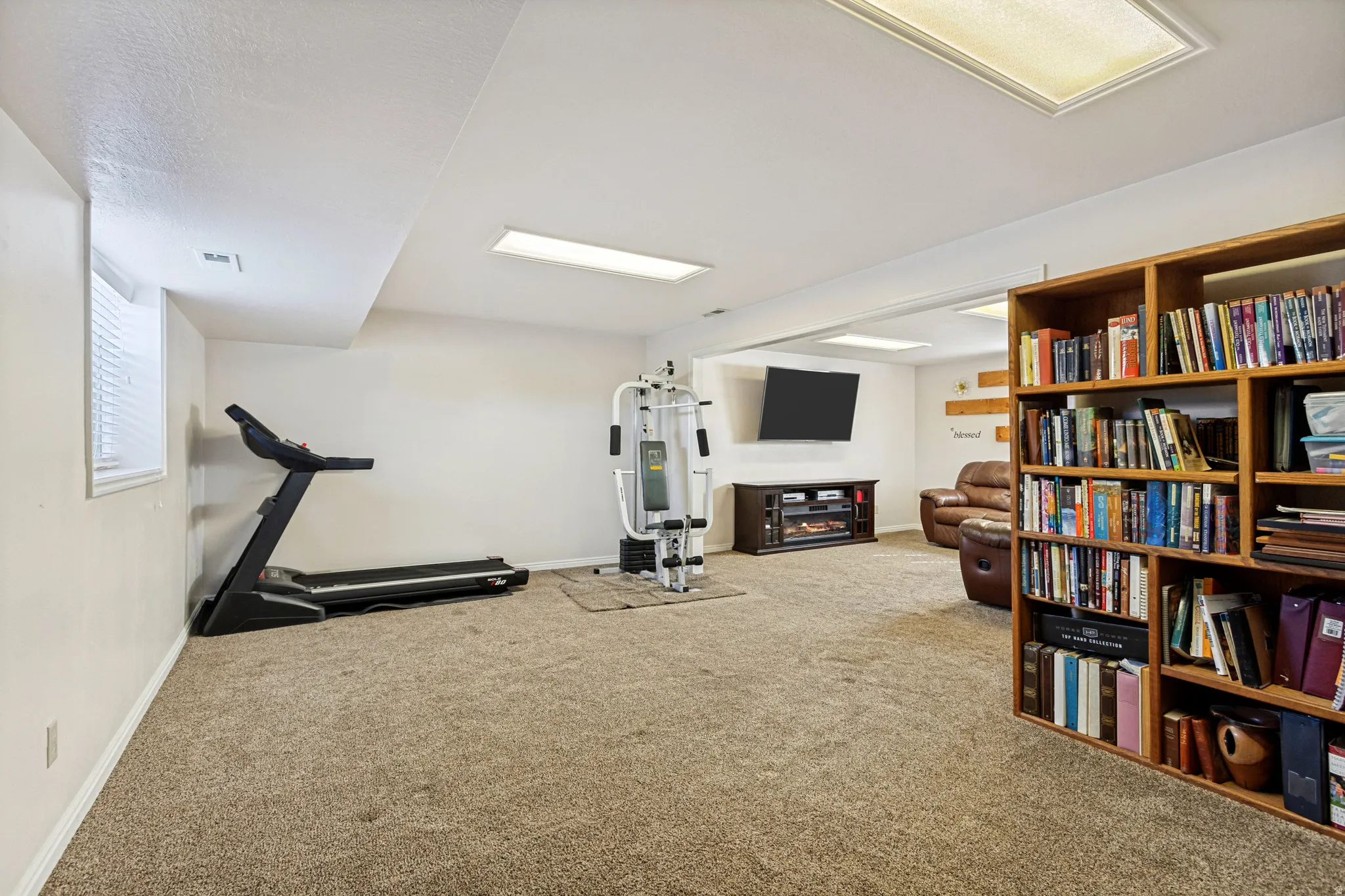Spacious room featuring carpet flooring, built-in shelving, recessed lighting, and a window for natural light
