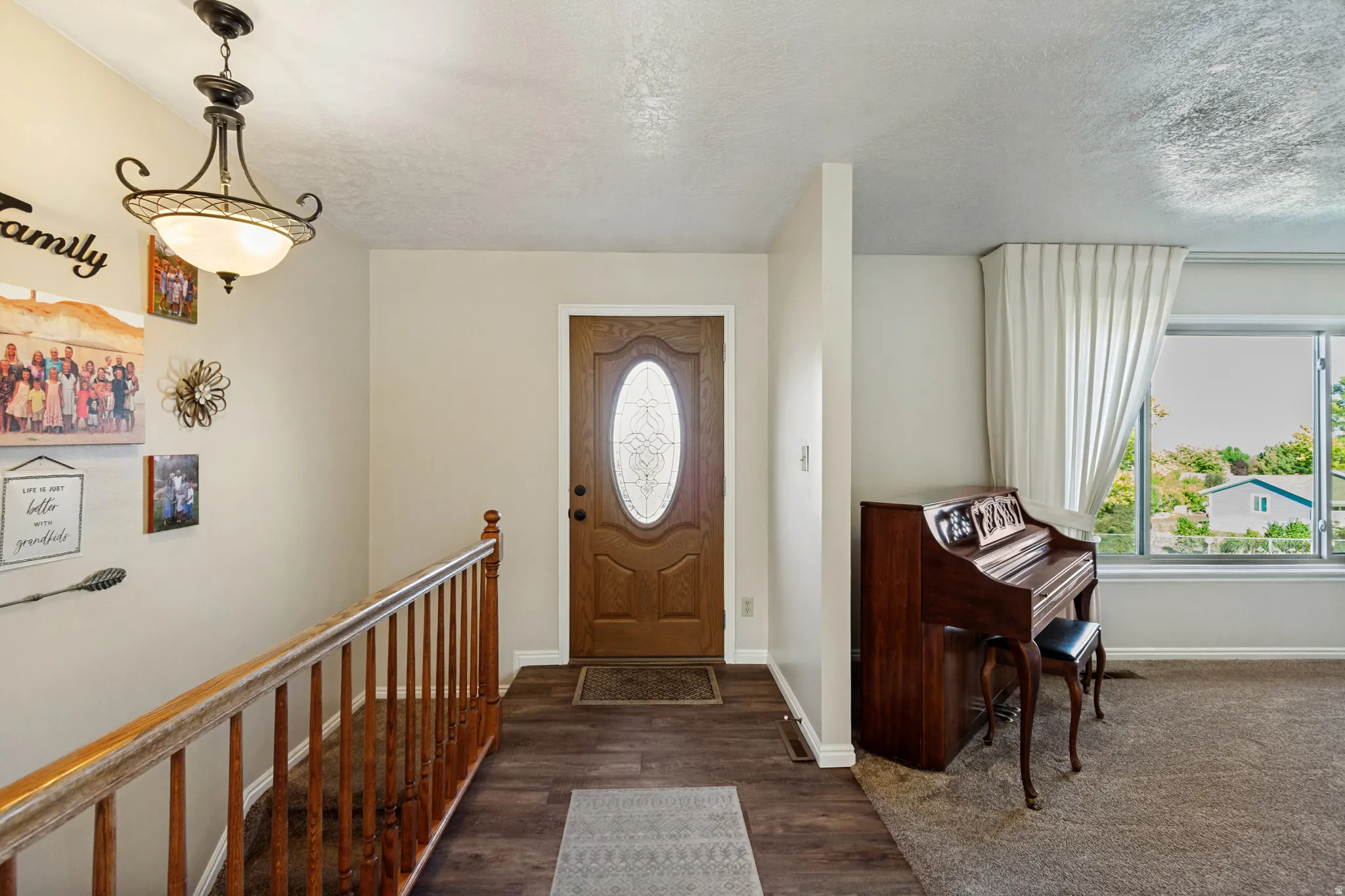Front entry with wood-finish flooring, an oval-paneled door, and a decorative overhead light fixture