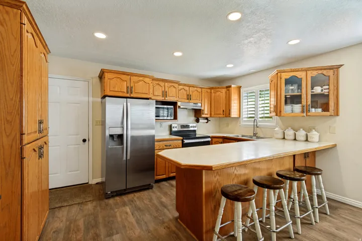 Kitchen featuring wood-finish cabinetry, stainless steel appliances, a breakfast bar, and recessed lighting