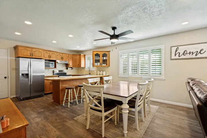 Wood-finish flooring throughout, kitchen featuring wood cabinetry, stainless steel appliances, and a breakfast bar
