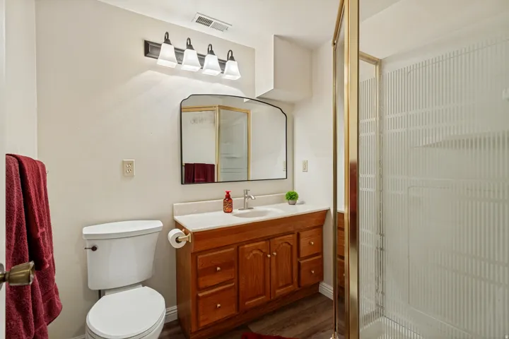 Wood-finish flooring with a vanity featuring a wood-tone finish, a white countertop, and a single basin sink
