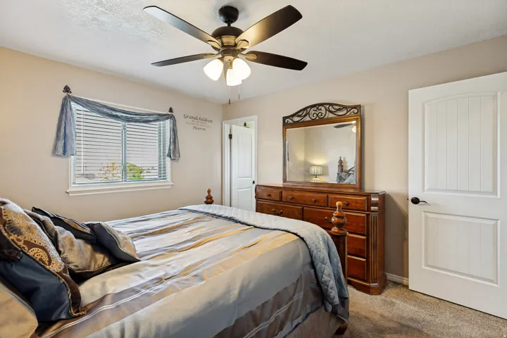 Ceiling fan with integrated lighting, window with blinds, paneled interior door with dark hardware, carpeting, and light neutral wall paint