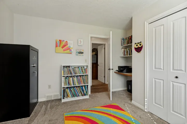 Built-in desk with shelving, bi-fold closet doors, and light gray wall paint