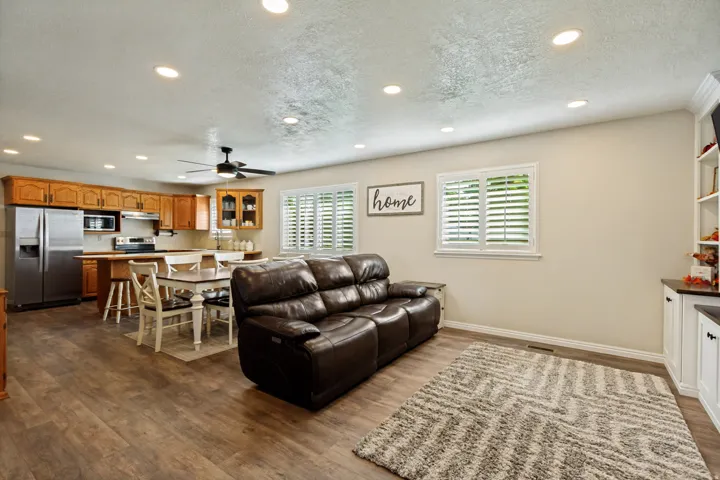 Open-concept living area featuring wood-finish flooring, recessed lighting, and white plantation shutters