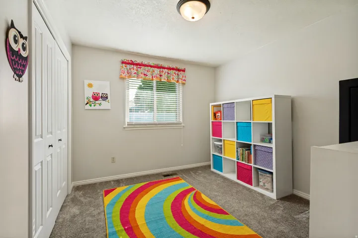 Neutral wall paint, textured ceiling, window with blinds, carpeted flooring, and a flush mount light fixture