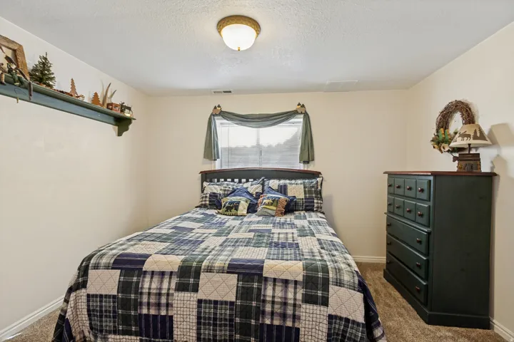 Wall-mounted shelf, carpeted flooring, and a single window with blinds