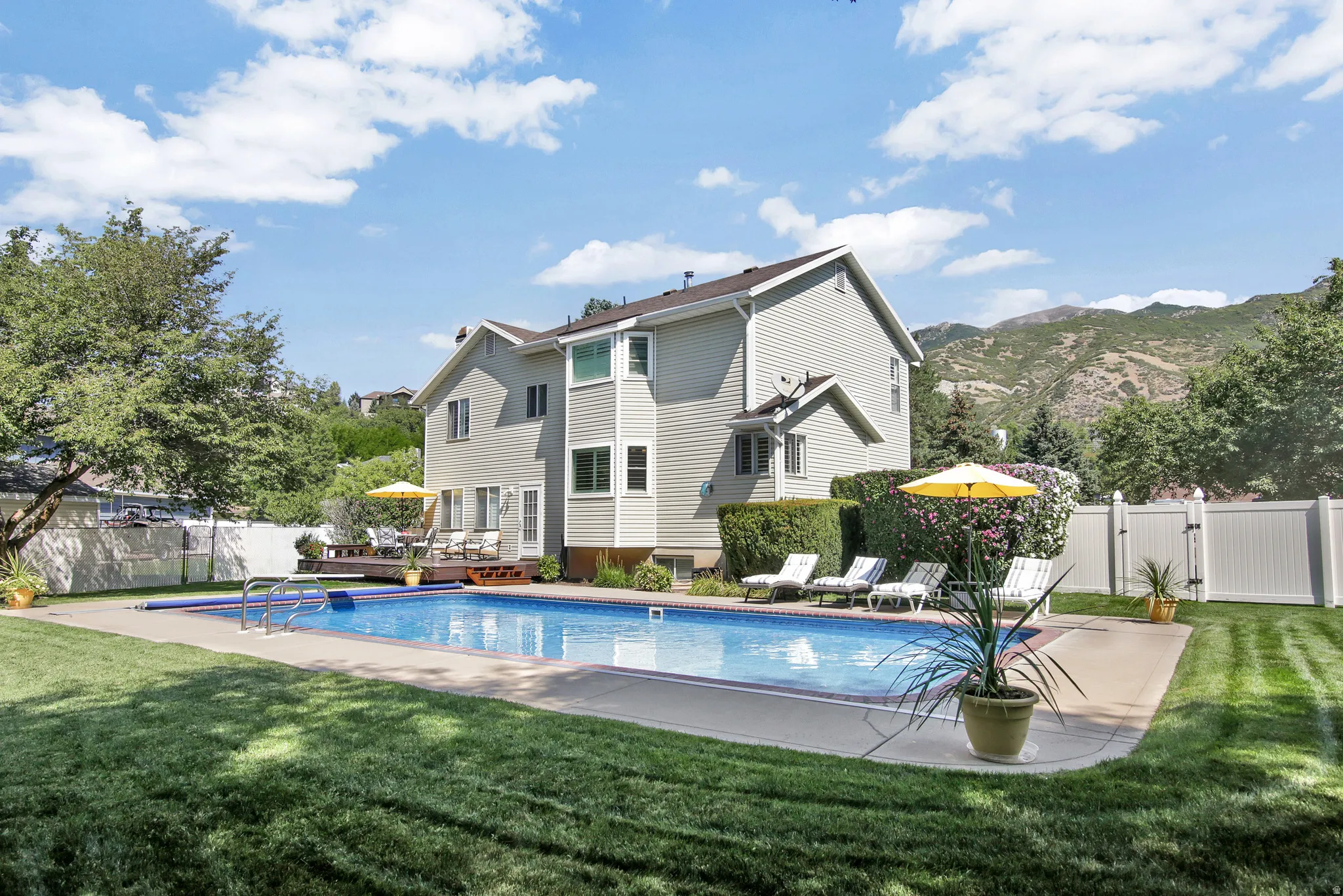 In-ground swimming pool with a concrete surround, wood deck, and a private fenced yard