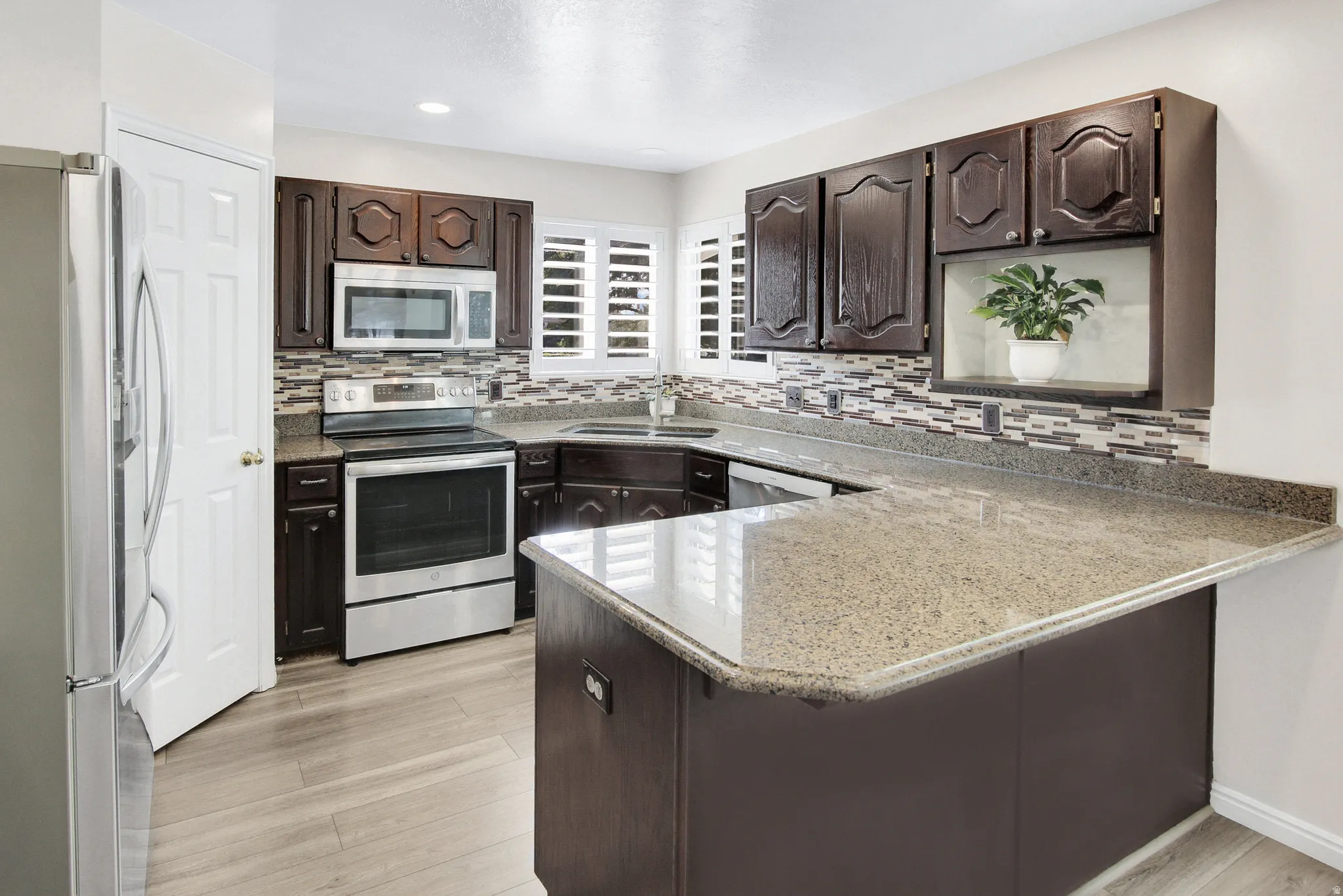 Kitchen with dark wood-finish cabinetry, light-toned countertops, and a mosaic tile backsplash