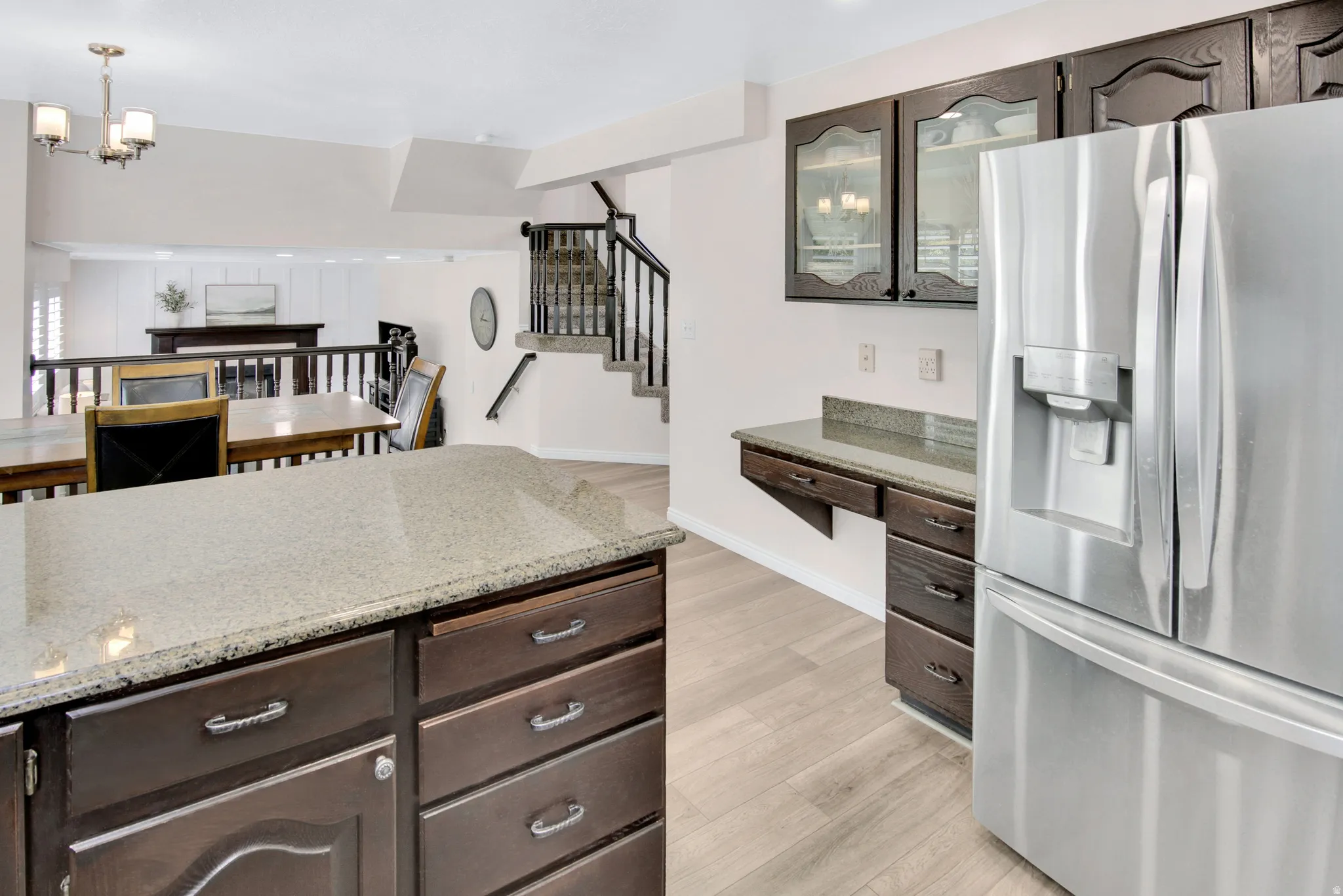 Stainless steel refrigerator, dark wood-finish cabinetry, light-toned wood-finish flooring, and a multi-level layout
