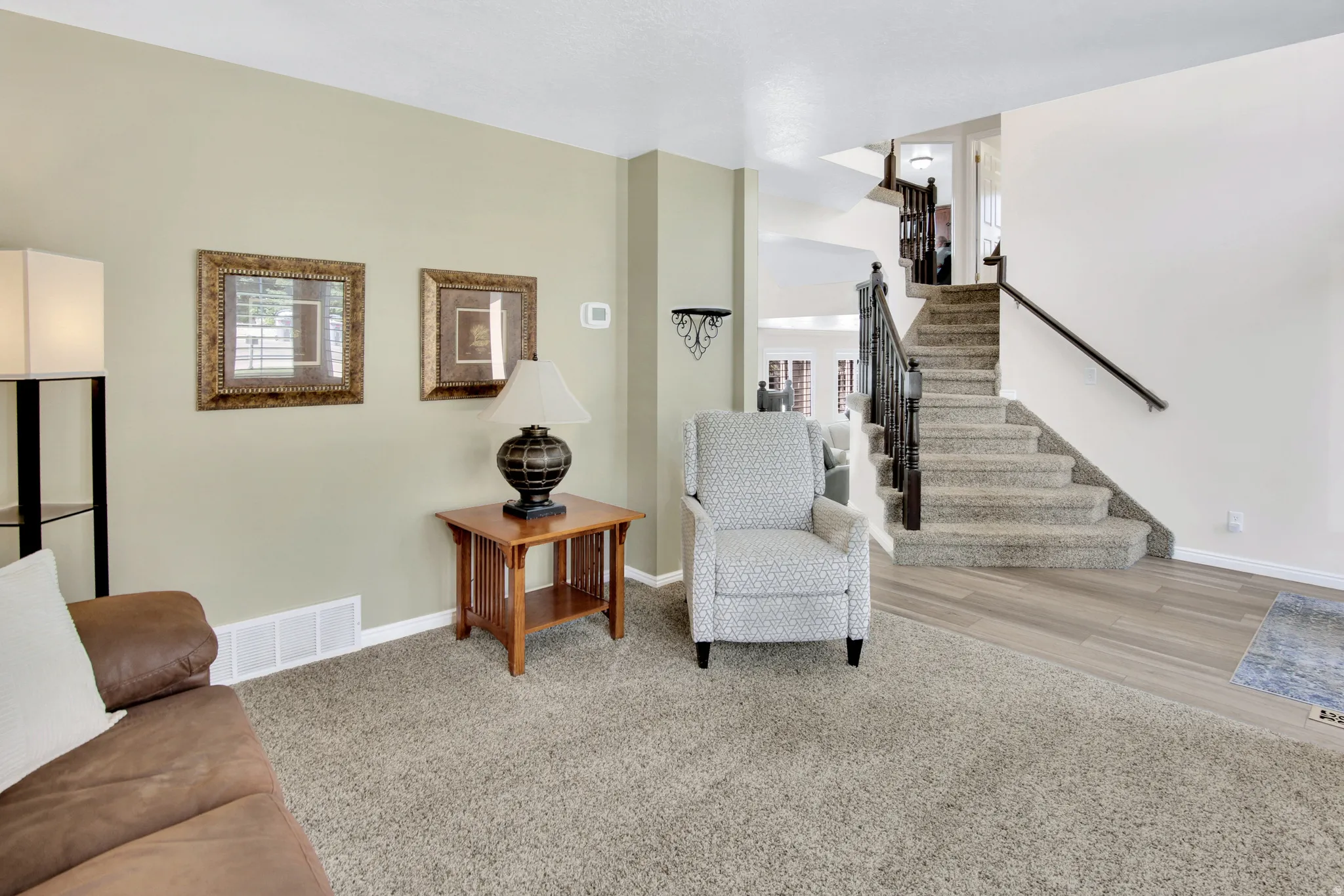 Carpeted flooring, wood-finish flooring, staircase with metal balusters and wood handrail, and light-toned wall paint