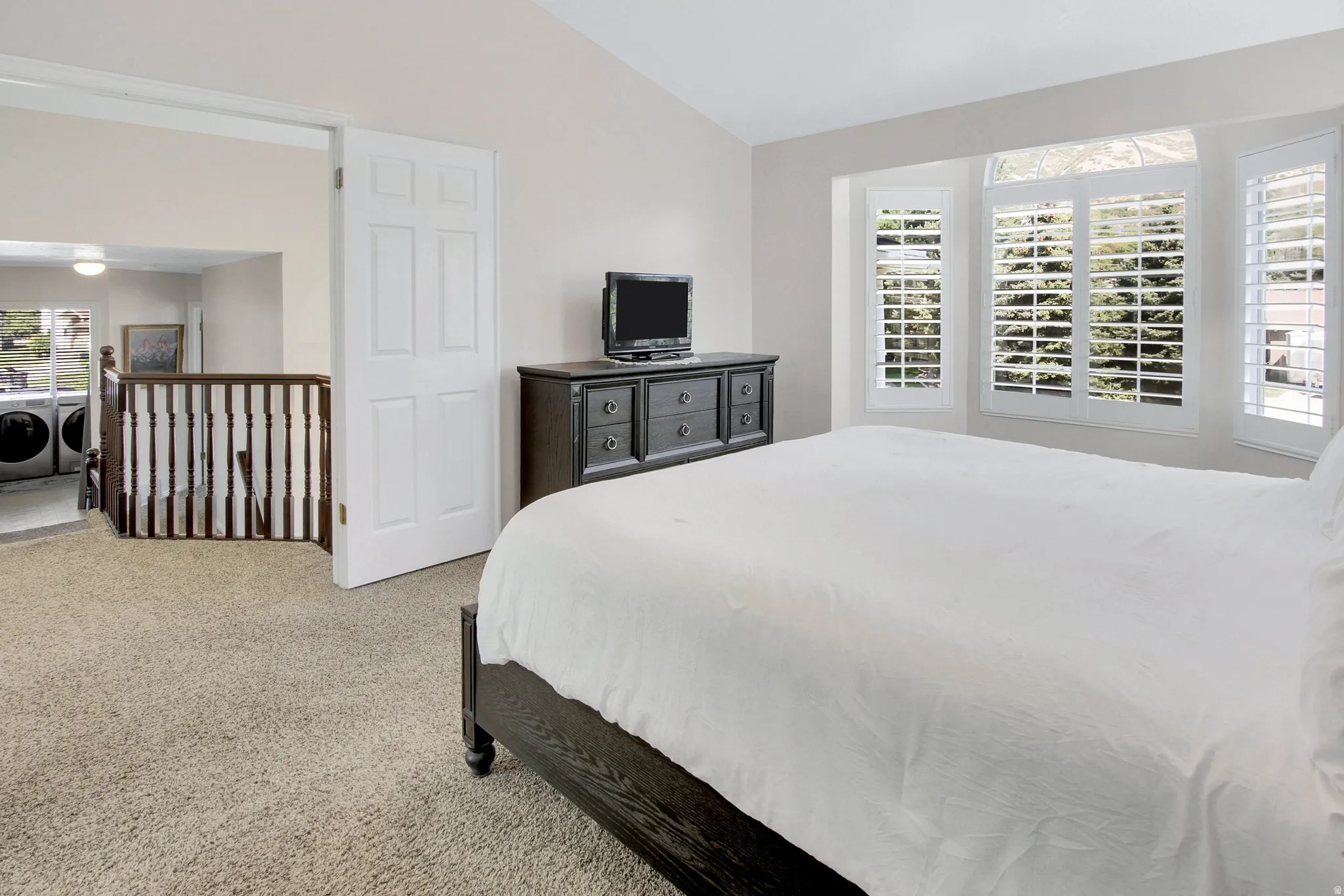 Primary Bedroom on it's own level. Vaulted ceiling with an overhead light fixture, bay window with plantation shutters, and mountain views