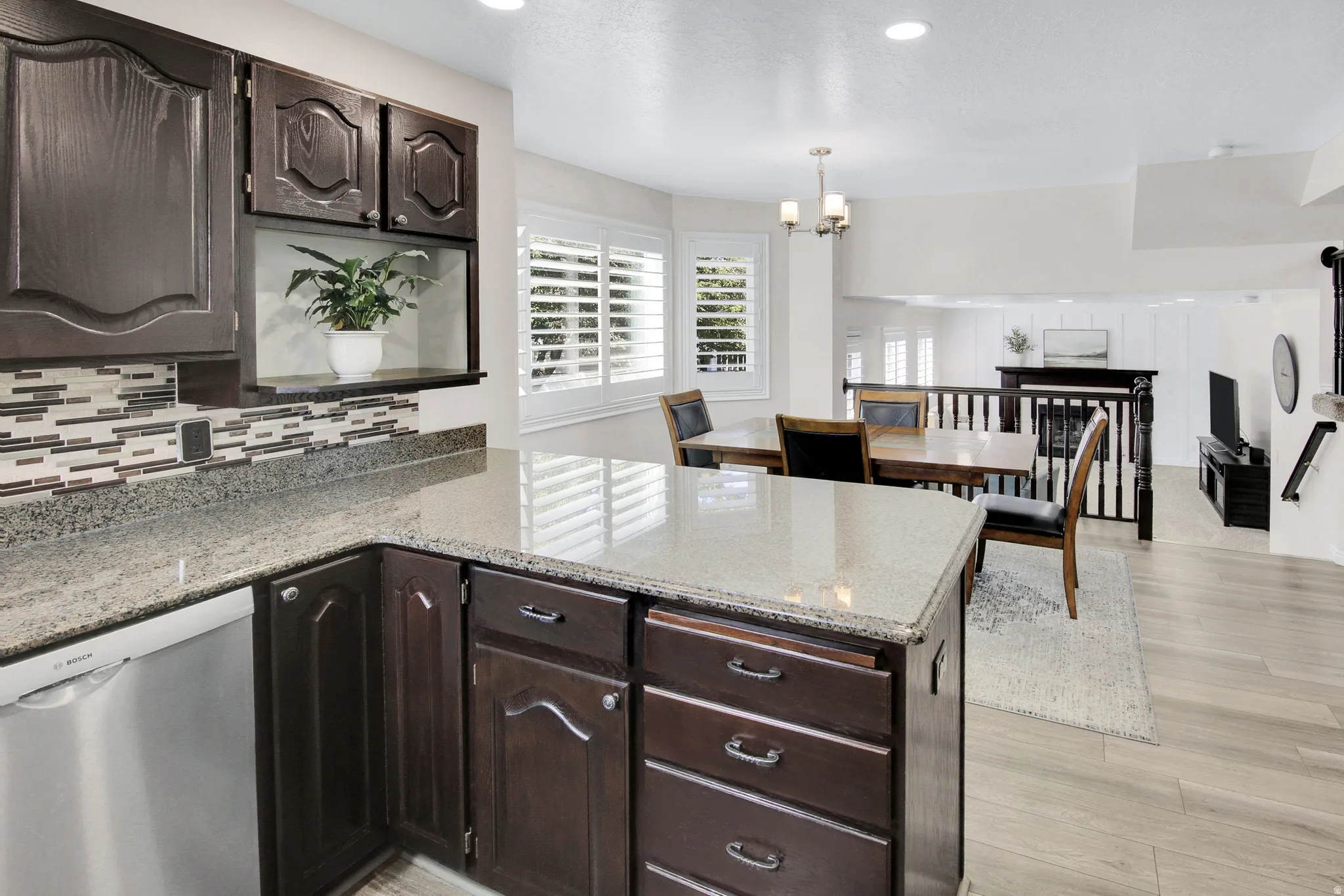 Kitchen featuring dark wood cabinetry, light-toned countertops, and a mosaic tile backsplash