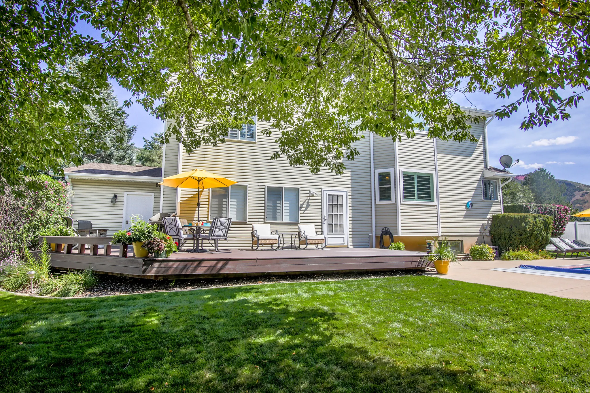Expansive backyard with a manicured lawn, a custom deck, patio and a beautiful yard.