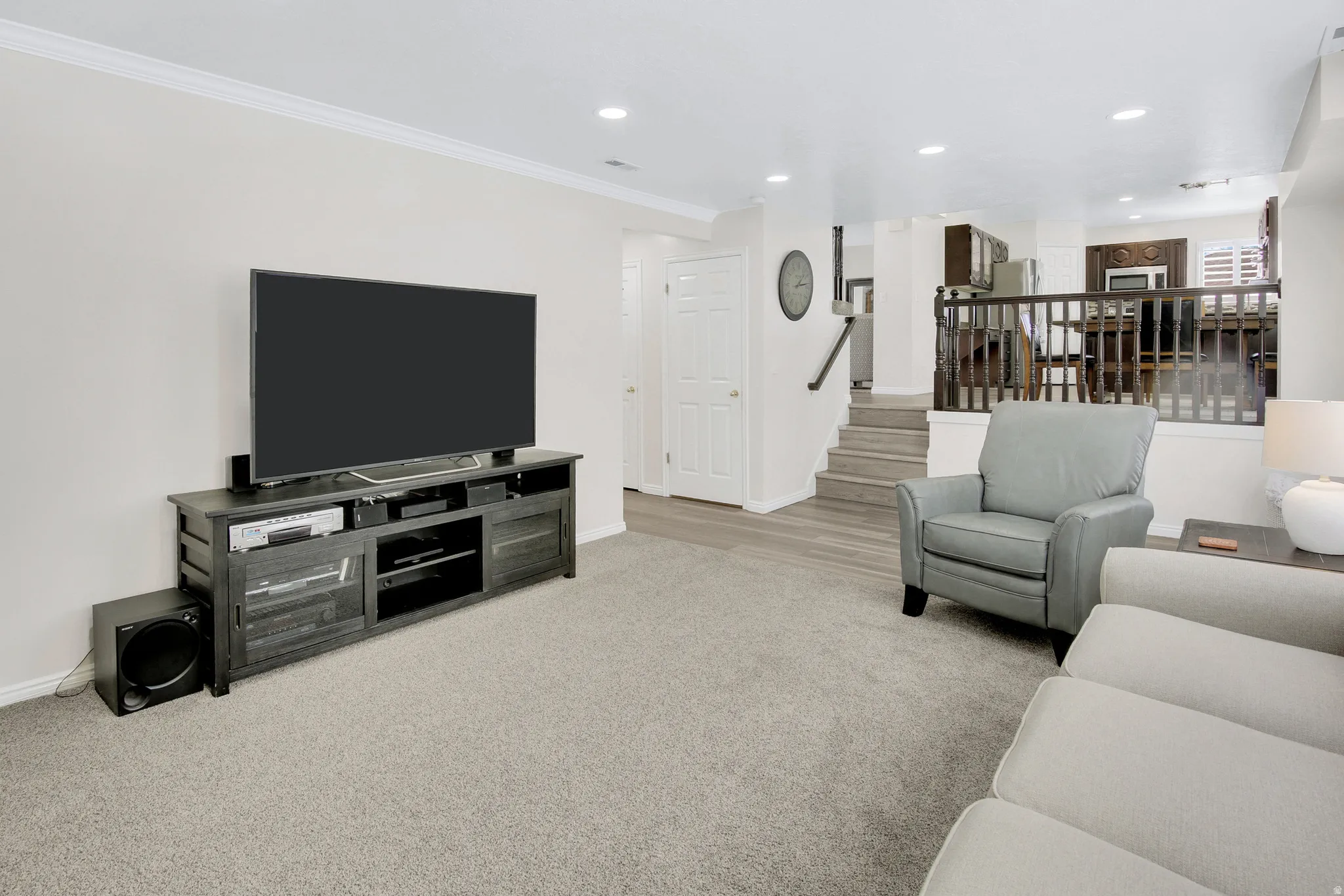 Recessed lighting, crown molding, wood-finish flooring, carpeted area, and wood newel post with balusters