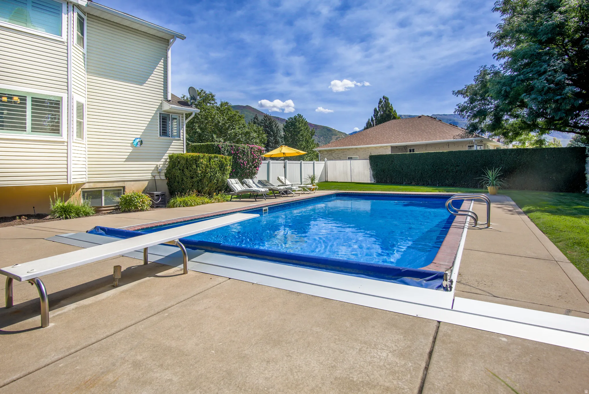 Swimming pool with a diving board, 8 ft. depth, surrounded by concrete decking and a manicured lawn
