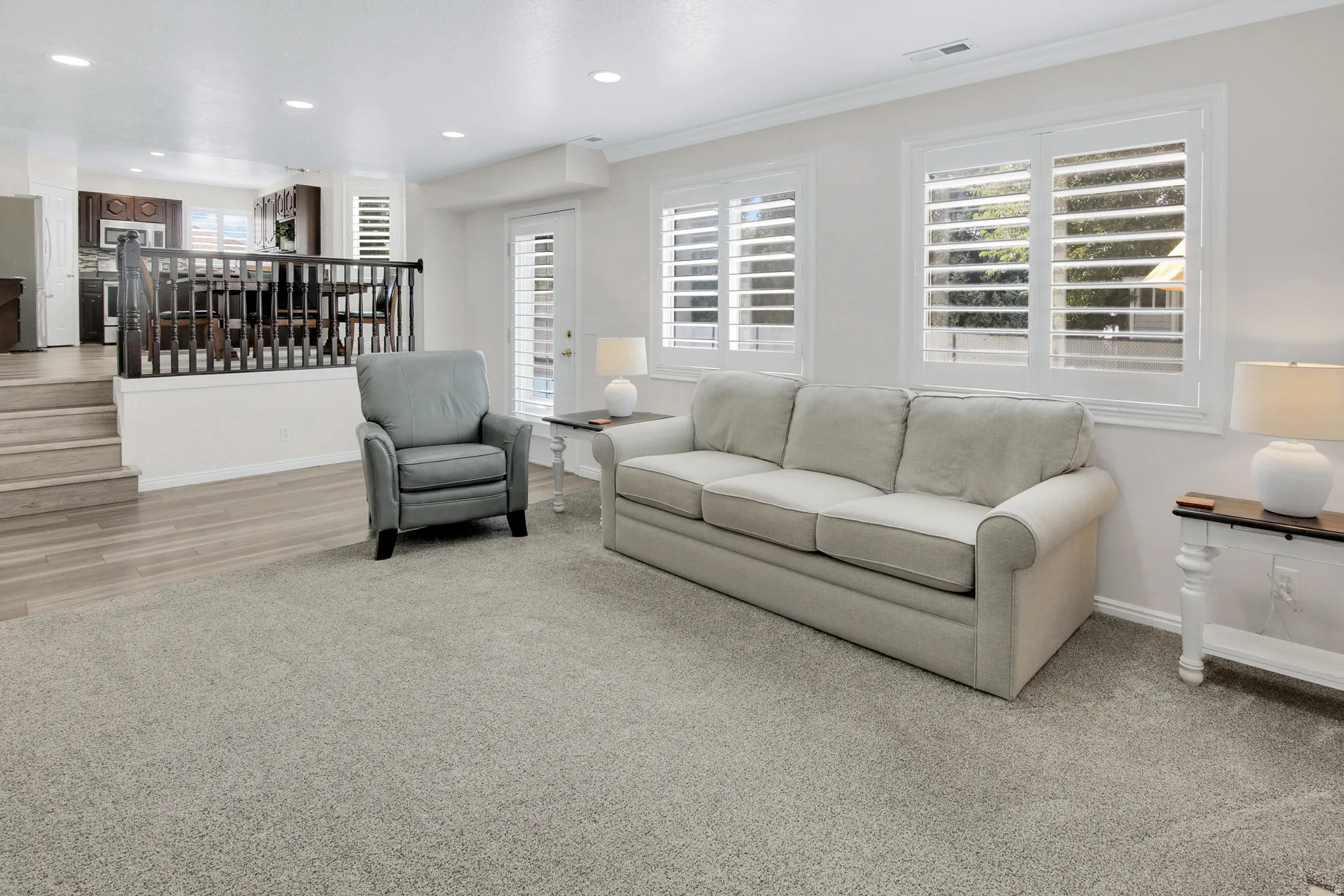 Recessed lighting illuminates the space, featuring white window shutters, a white paneled door, and durable wood-finish steps