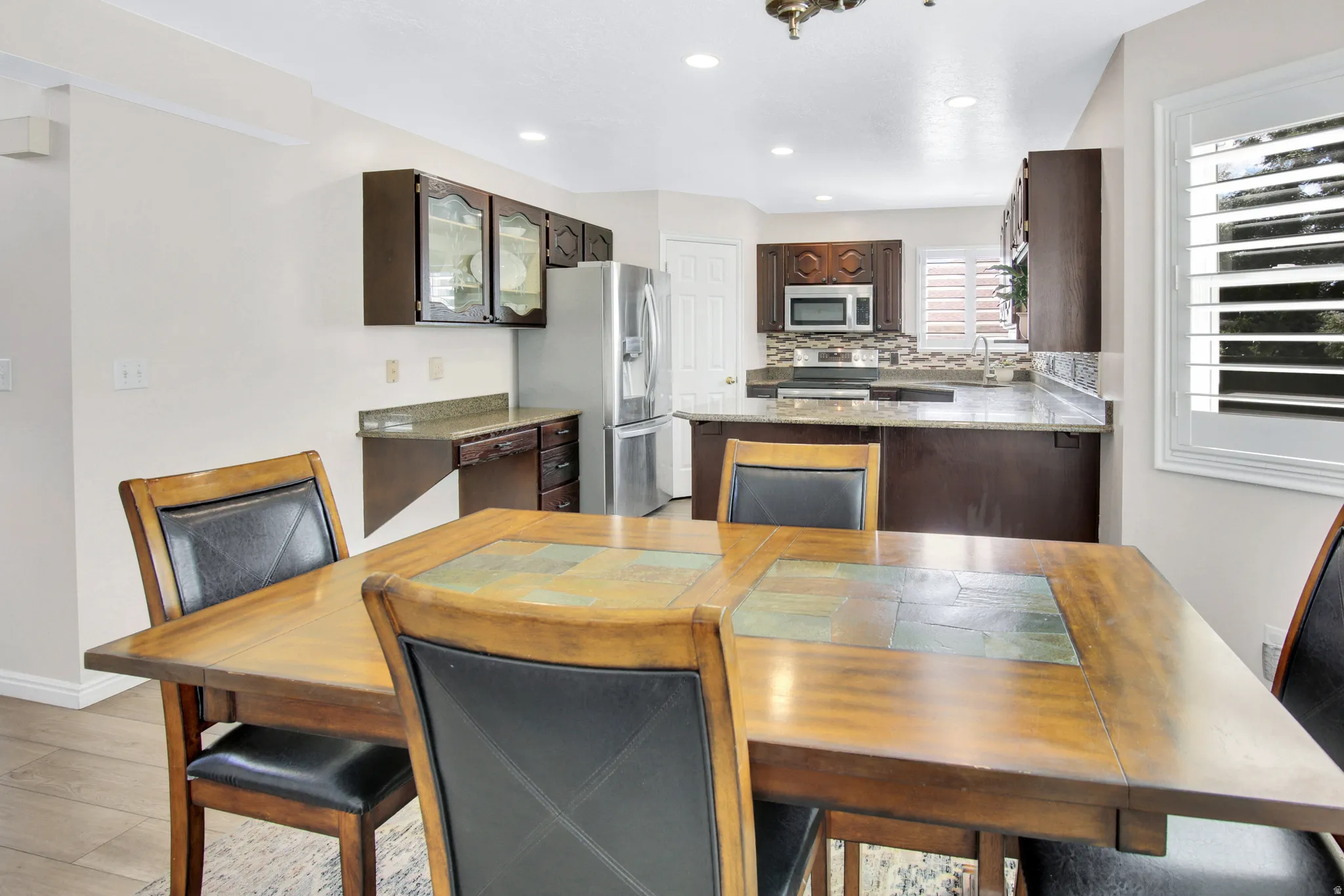 Kitchen featuring dark wood cabinetry, stainless steel appliances, light-toned countertops, and a tiled backsplash