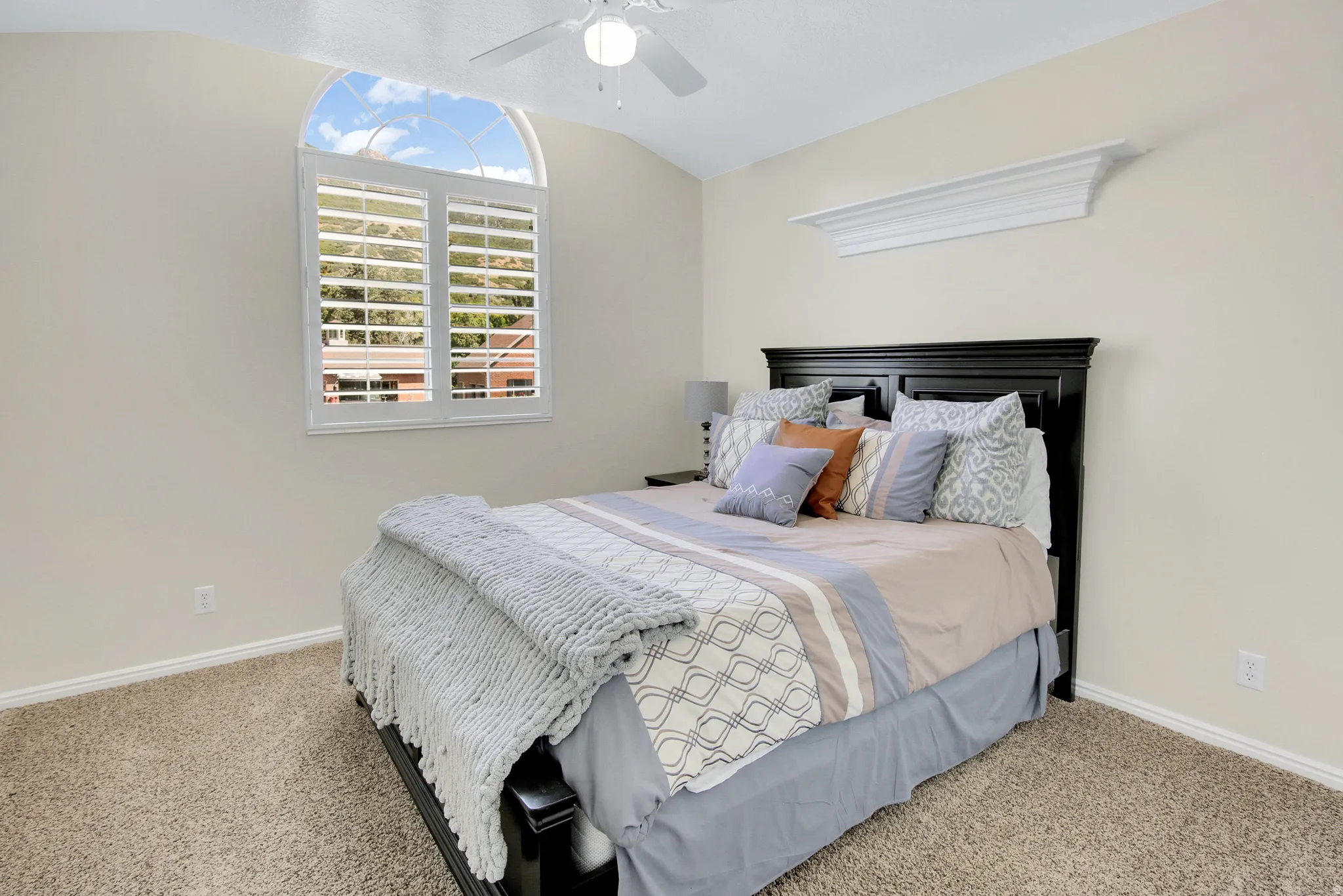 Bedroom #3 Vaulted ceiling with a ceiling fan, arched window with plantation shutters, crown molding detail, and beautiful Veiws!
