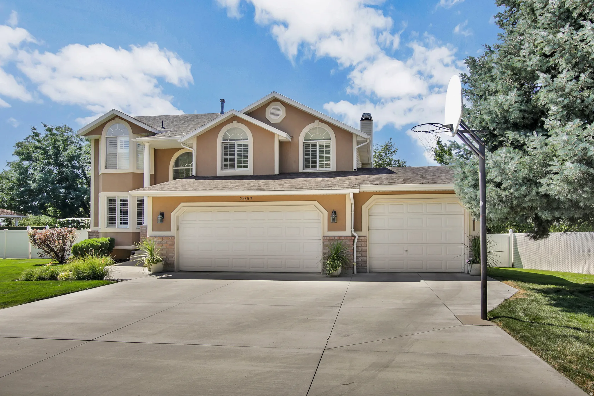 Stucco exterior with brick accents, arched windows, and a Three-car garage. one bay is extra deep for TRUCKS
