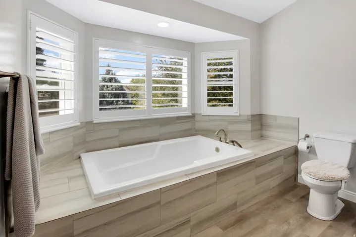Primary Bath with Built-in soaking tub surrounded by beautiful tile and bay window.