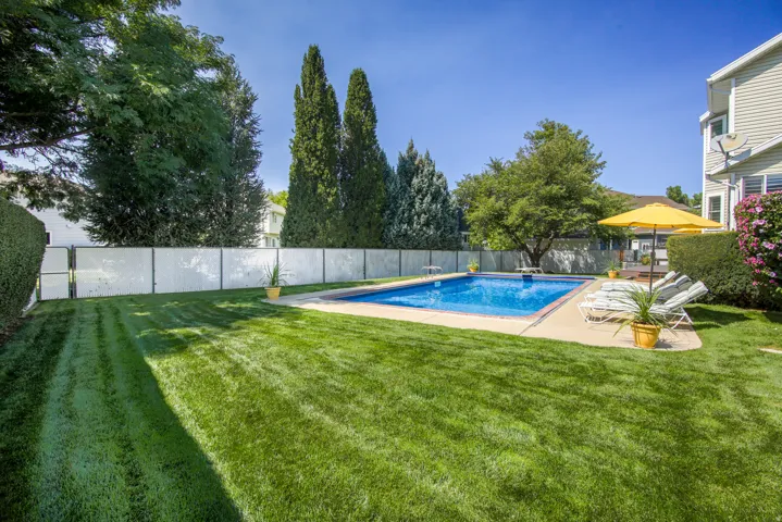 Expansive backyard featuring a fantastic swimming pool, concrete pool deck, and lush green lawn