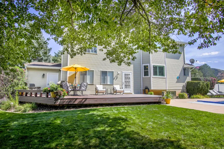 Expansive backyard with a manicured lawn, a custom deck, patio and a beautiful yard.