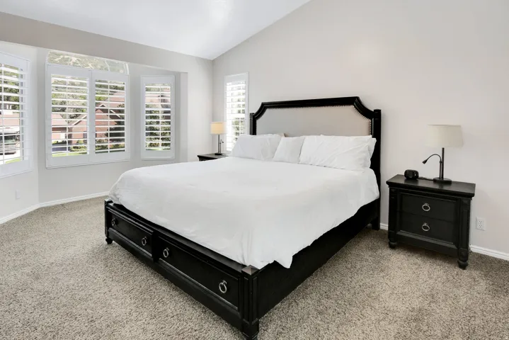 Primary Bedrooms with Vaulted ceiling, bay window, plantation shutters, and large walk in closet