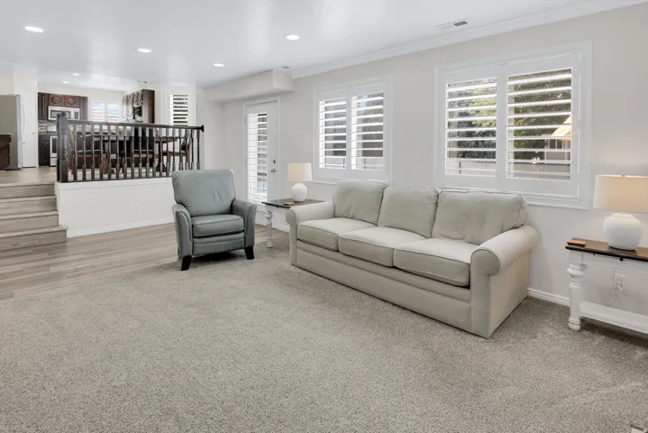Recessed lighting illuminates the space, featuring white window shutters, a white paneled door, and durable wood-finish steps