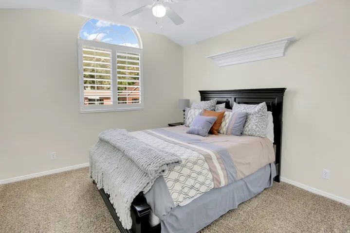 Bedroom #3 Vaulted ceiling with a ceiling fan, arched window with plantation shutters, crown molding detail, and beautiful Veiws!