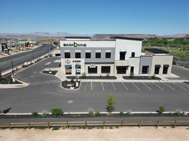 Modern commercial building with multiple storefronts, ample parking, and an adjacent roadway
