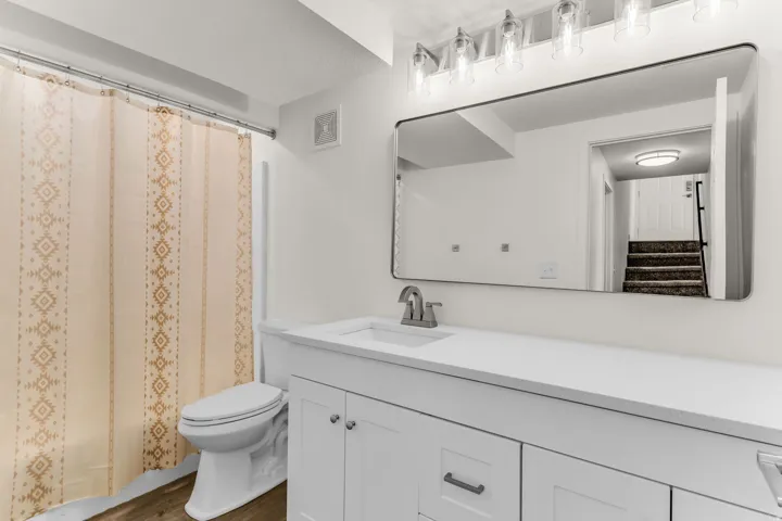 White vanity with shaker-style cabinetry, a white countertop, and a rectangular undermount sink