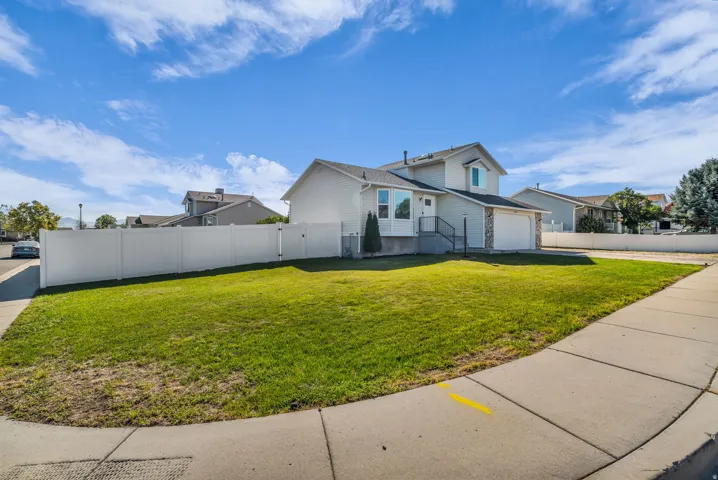Two-story residence with a two-car garage, stone accent siding, and a white privacy fence