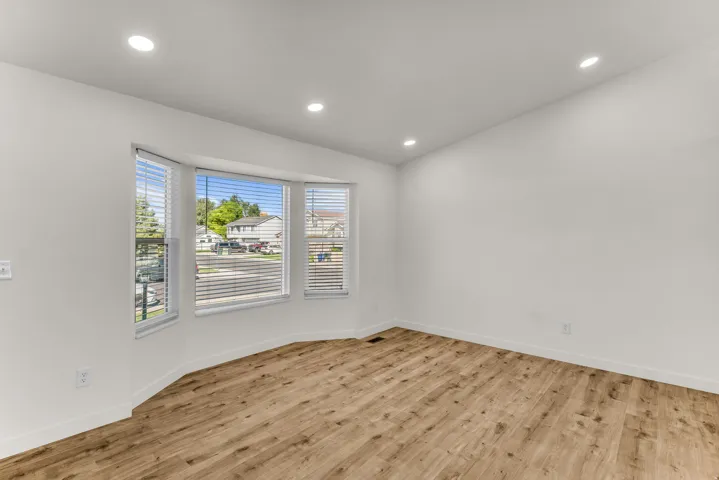 Bay window with horizontal blinds, wood-finish flooring, and recessed ceiling lights