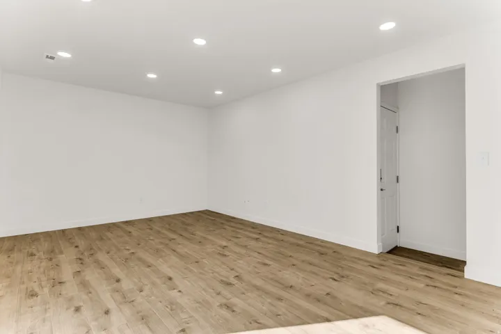 Recessed ceiling lighting, wood-finish flooring, and white walls