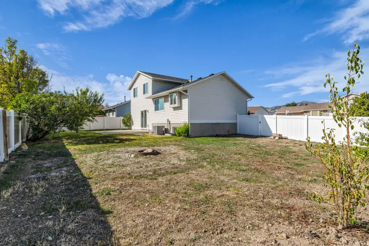 Expansive backyard with a full perimeter fence, mature trees, and a ground-level patio