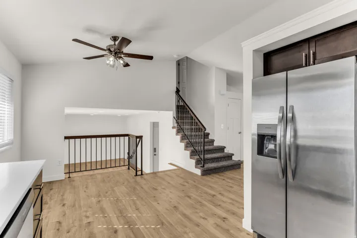 High ceilings featuring a ceiling fan, wood-finish flooring, a stainless steel refrigerator, and dark wood-finish cabinetry