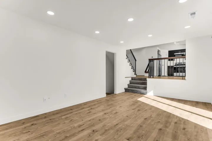 Wood-finish flooring, recessed lighting, and a staircase with a black metal railing