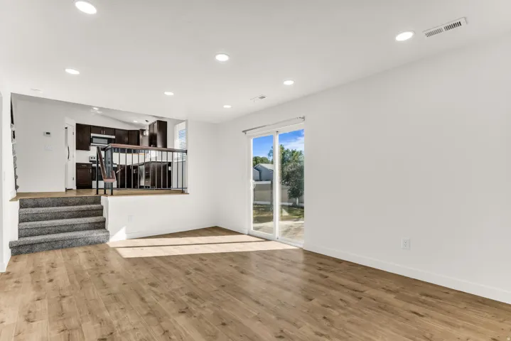 Open-concept living area featuring wood-finish flooring, recessed lighting, and a sliding glass door