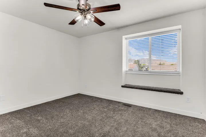 Recessed window with a broad sill, ceiling fan with integrated lighting, and neutral-toned carpeting