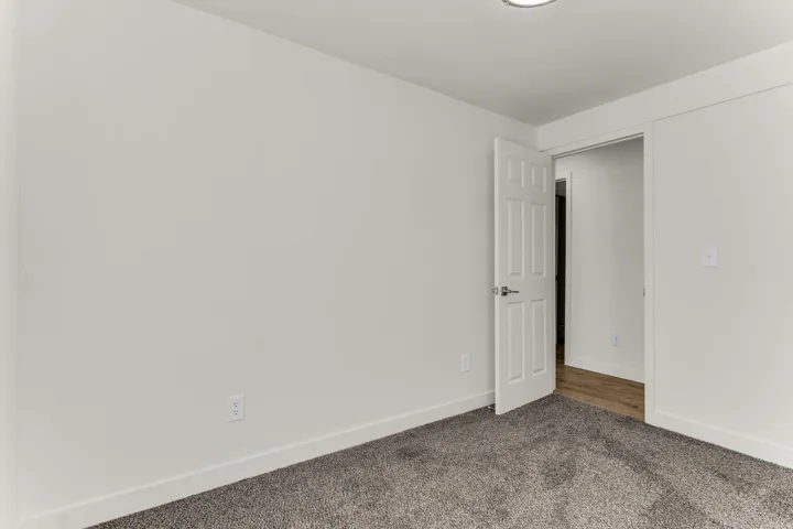 Neutral wall color, textured carpeting, panel door, and recessed ceiling light