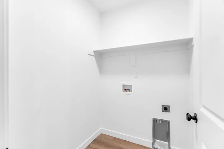 Laundry area with a built-in shelf, appliance hookups, and wood-finish flooring