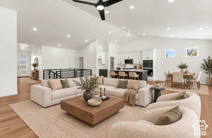 Vaulted ceilings with recessed lighting, wood-finish flooring, modern black railing, kitchen island with built-in appliances, and a dining area