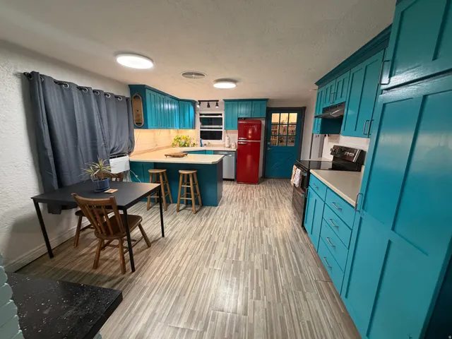 Kitchen featuring vibrant blue cabinetry, light-colored countertops, a kitchen island, and wood-finish flooring
