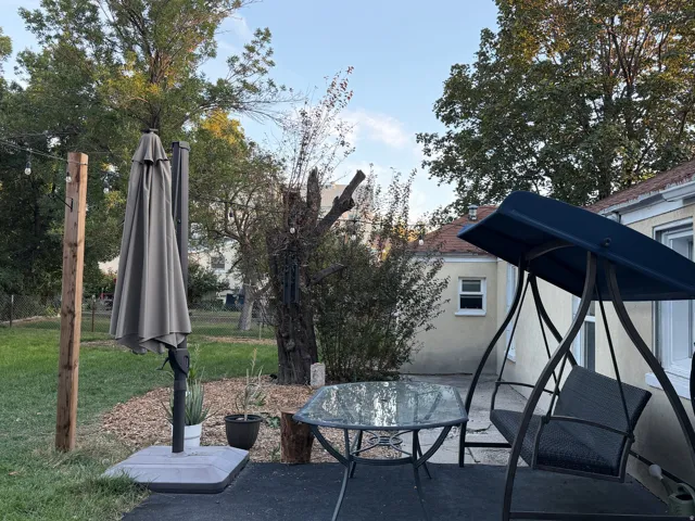 Paved patio area, string lighting, mature trees, and a manicured lawn